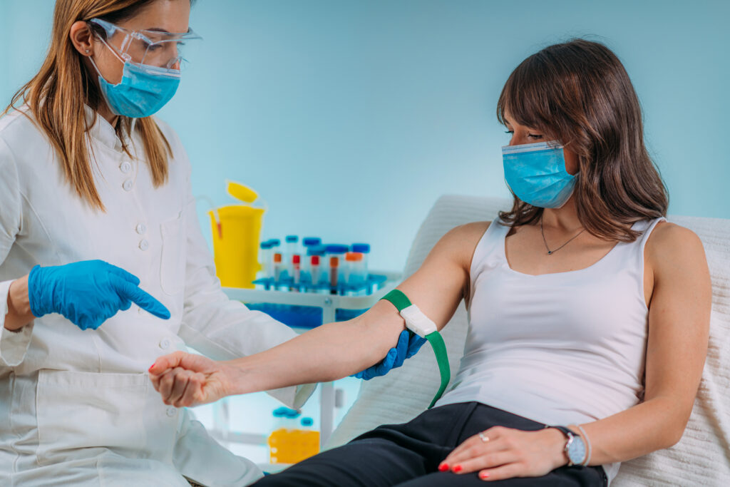A phlebotomist taking blood from her patient